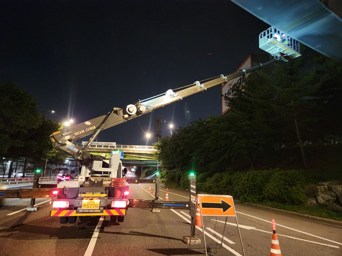 야간 도로 현장에서 작업 조명을 켜고 붐대를 펼친 스카이차
